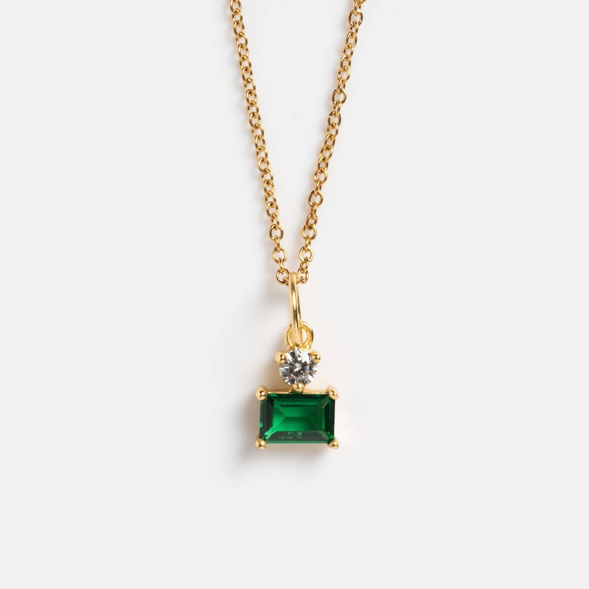 The My Cherie Necklace features a delicate gold chain with a rectangular emerald cubic zirconia pendant and a small round clear gemstone above it, displayed on a white background.