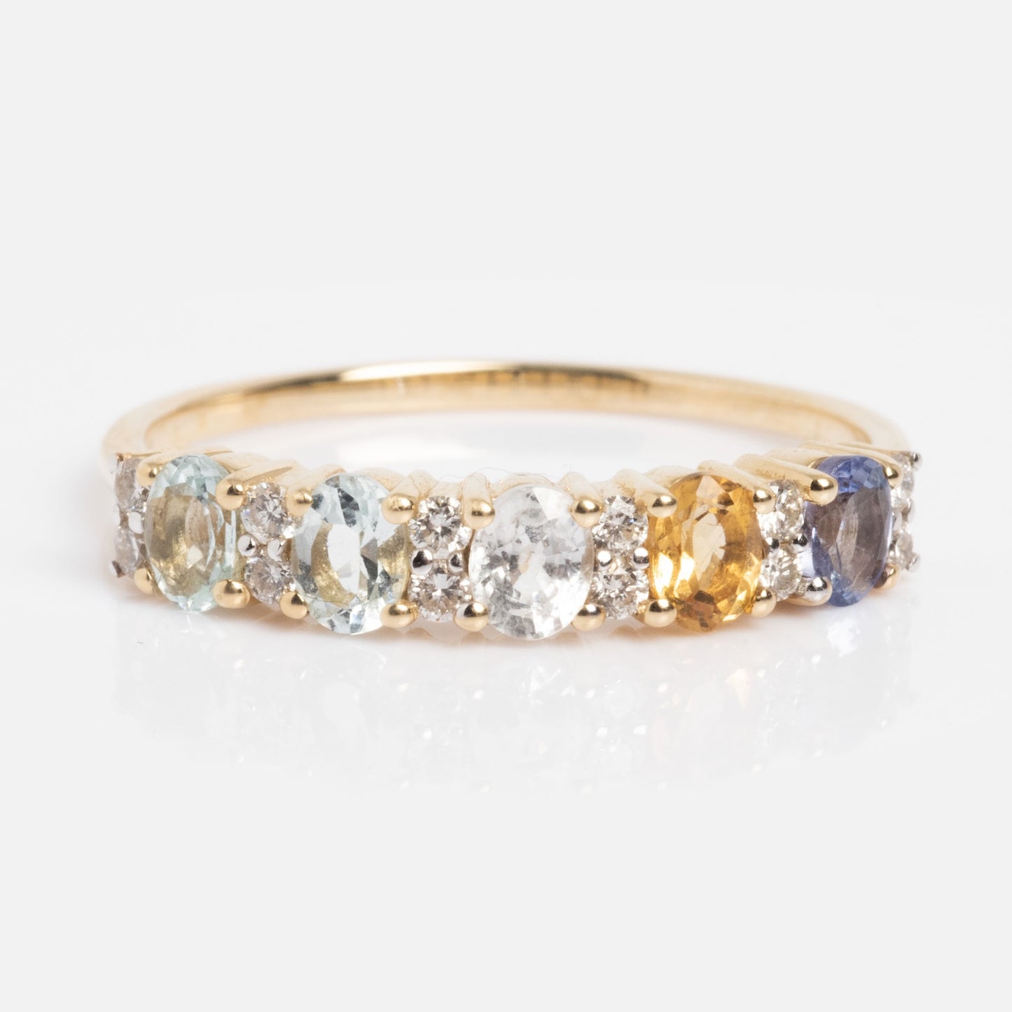 The Customizable Acrostic Oval Gemstone Ring features aquamarine, white sapphire, citrine, and tanzanite gemstones set in gold with white accent stones, shown here in size 9 against a white background.