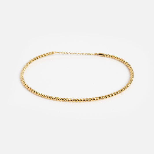A sample of the Twisted Brass Bangle with a smooth, polished finish is displayed on a plain white background.