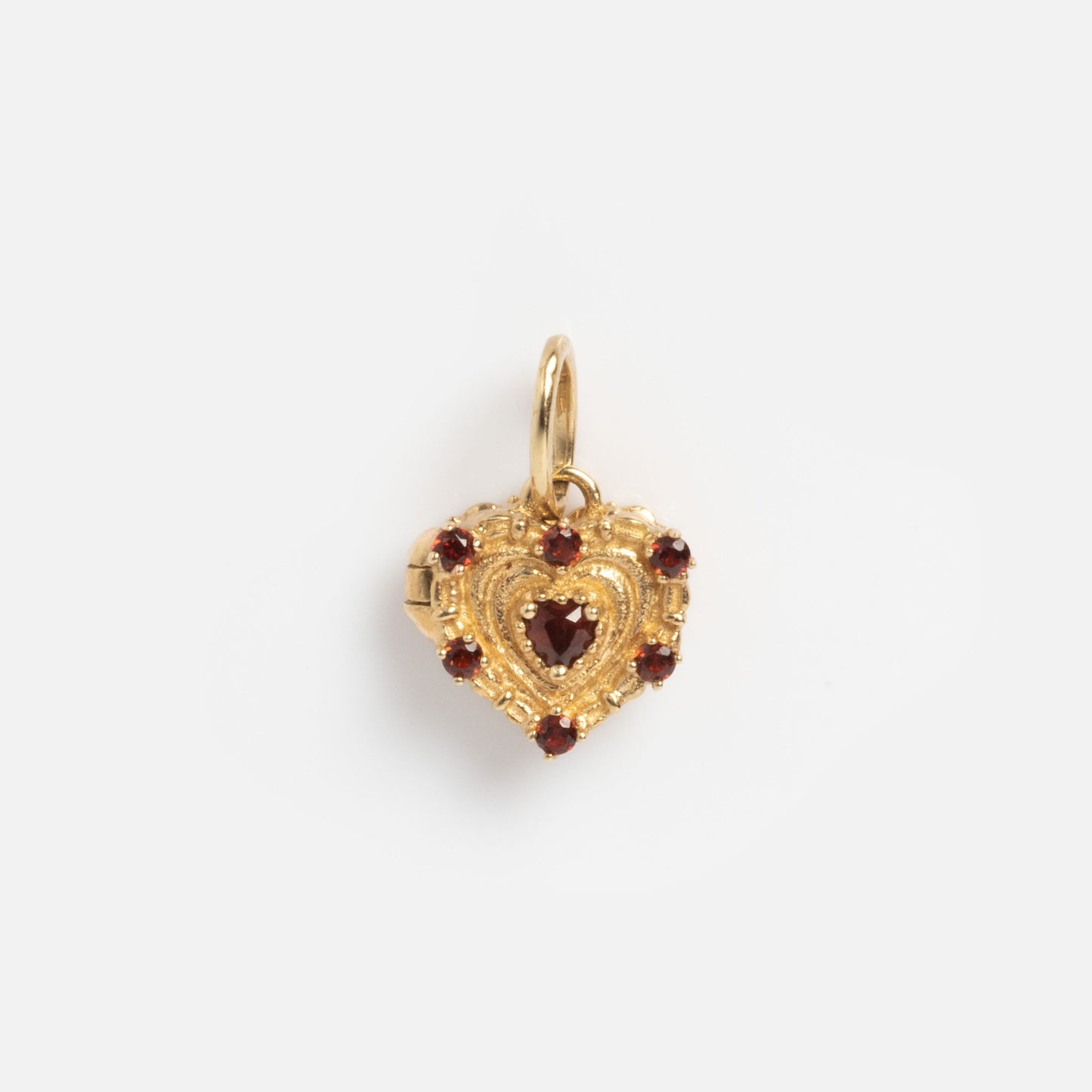 The Solid Gold Vintage Inspired Heart Cake Sample features a heart-shaped design with intricate detailing, a central red gemstone, and additional red stones along the border, displayed against a plain white background.
