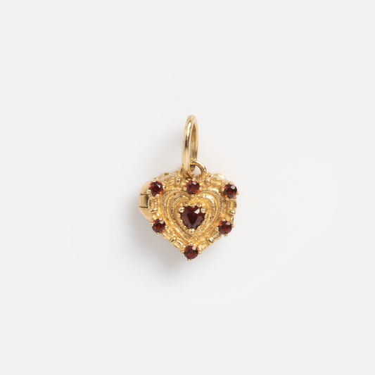 The Solid Gold Vintage Inspired Heart Cake Sample features a heart-shaped design with intricate detailing, a central red gemstone, and additional red stones along the border, displayed against a plain white background.