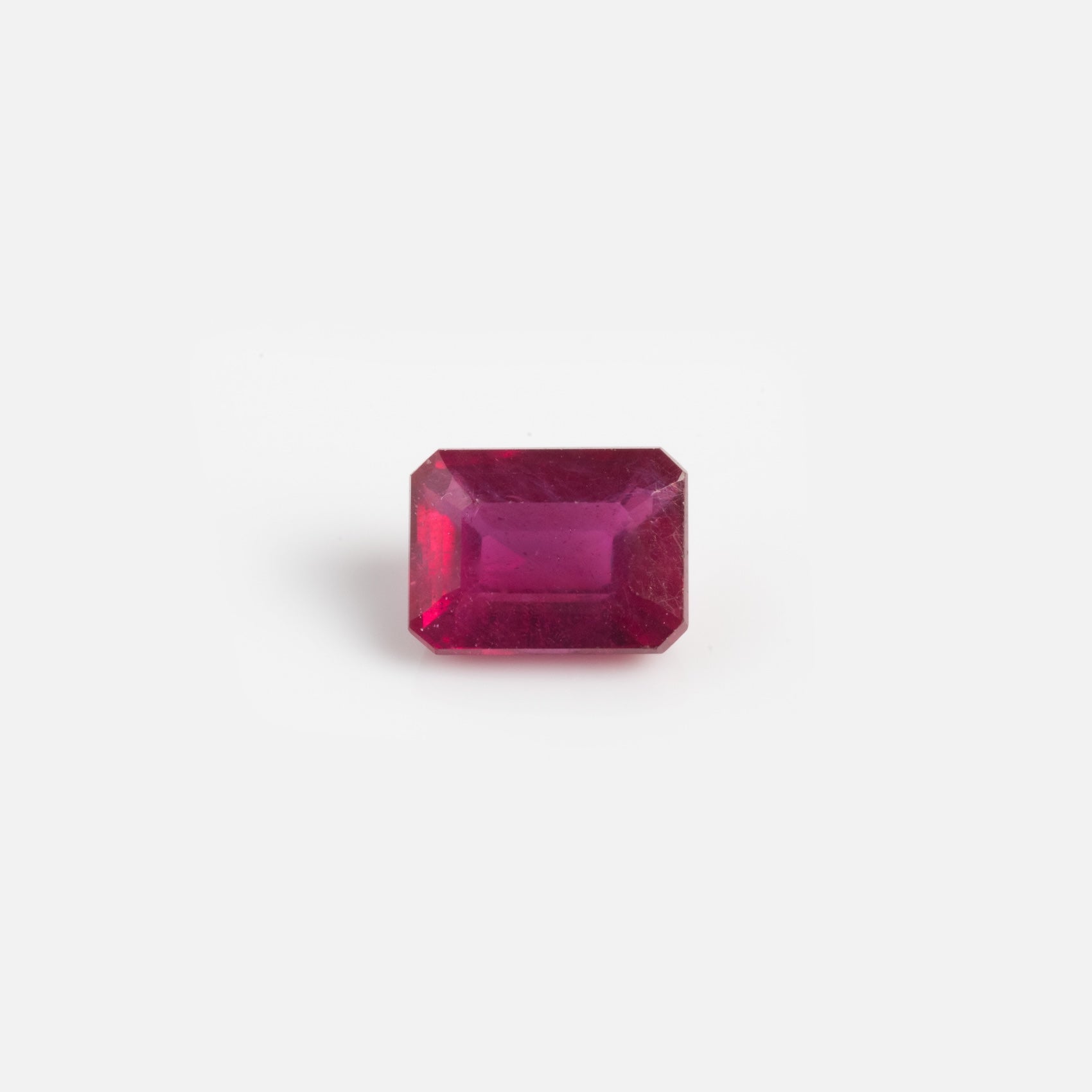 A 2.7 carat loose ruby sample, rectangular and faceted with beveled edges, is displayed against a plain white background.