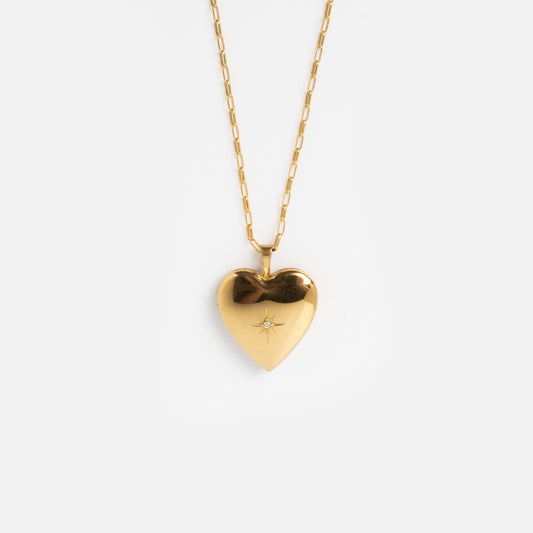 The 14k Gold Filled Heart of Gold Locket Sample features a heart-shaped pendant with a delicate chain and a star engraving at the center, showcased on a plain white background.