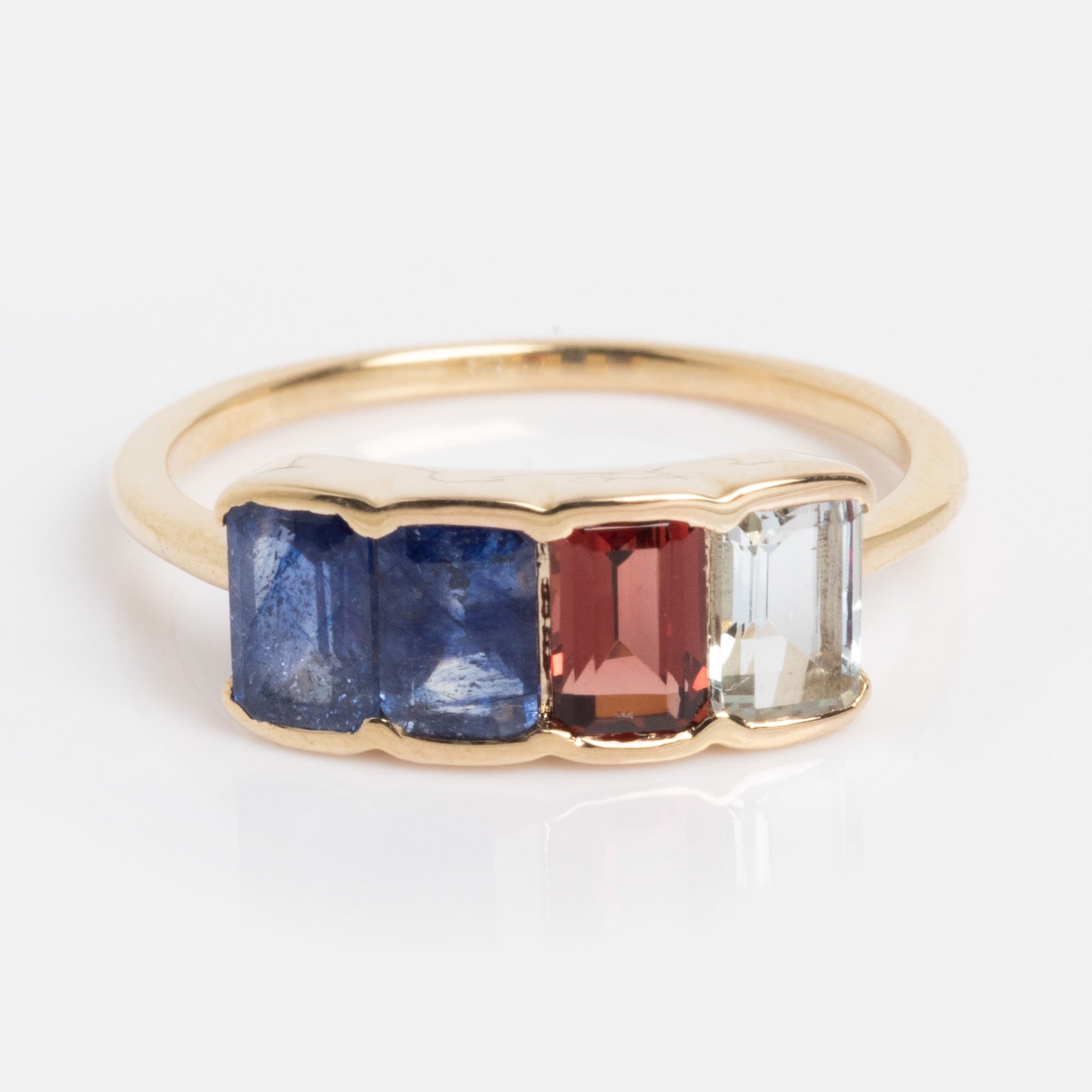 The Customizable Acrostic Baguette Gemstone Ring features tanzanite, garnet, and aquamarine baguette stones set side by side in a modern bezel setting; shown here in size 4 as a sample.