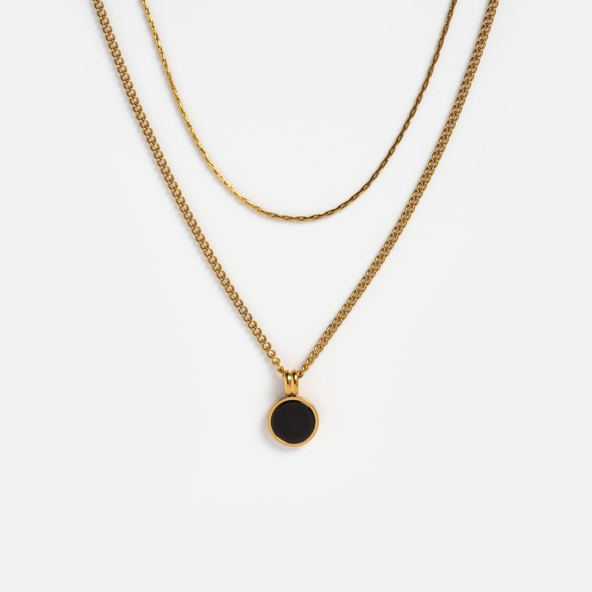 Two gold necklaces are shown on a white background: one is the Billie Necklace chain, and the other has a small round black coin pendant in gold, creating an elegant layered necklace style.