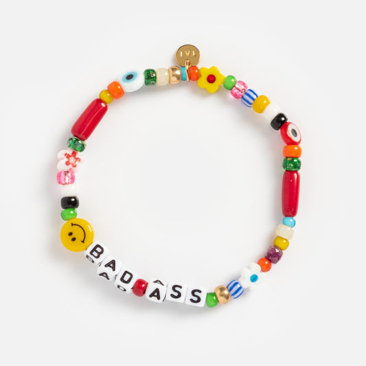 The Handmade Beaded Bada$$ Bracelet features colorful beads in various shapes and patterns, including a yellow smiley face and white letter beads spelling Bada$$, plus 14k gold plated details for extra shine.