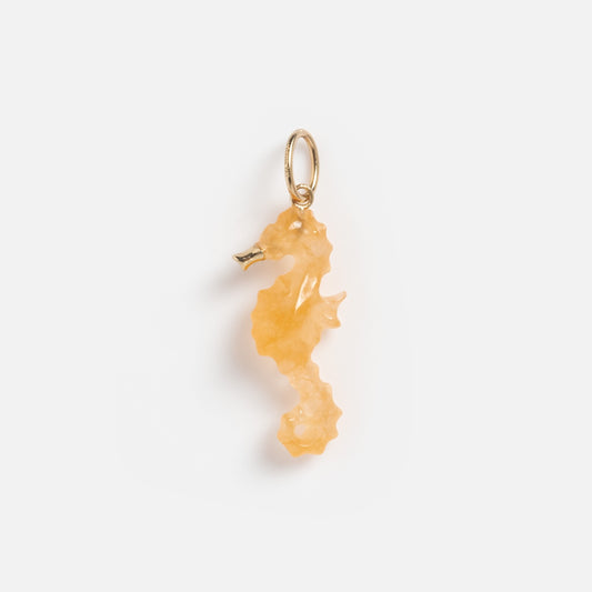 The Solid Gold Under The Sea Charm, shaped like a seahorse, features an amber-like translucent body with a gold loop and glows with siren allure against a plain white background.