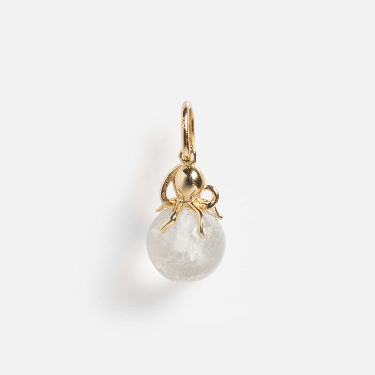 The Solid Gold Under The Sea Charm is a small pendant showcasing a gold octopus atop a glowing round white stone, set against a plain white background.