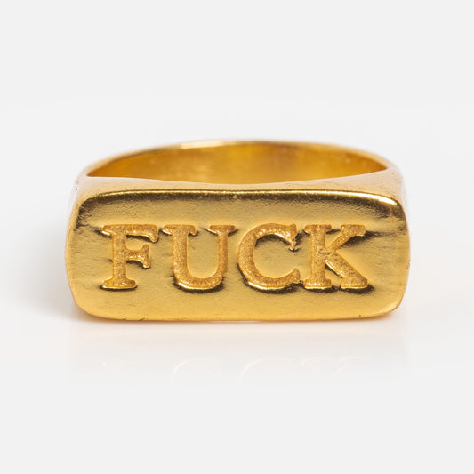 The Bold Fuck Ring is an 18k gold plated signet ring with a rectangular face engraved with the word FUCK in bold capital letters.