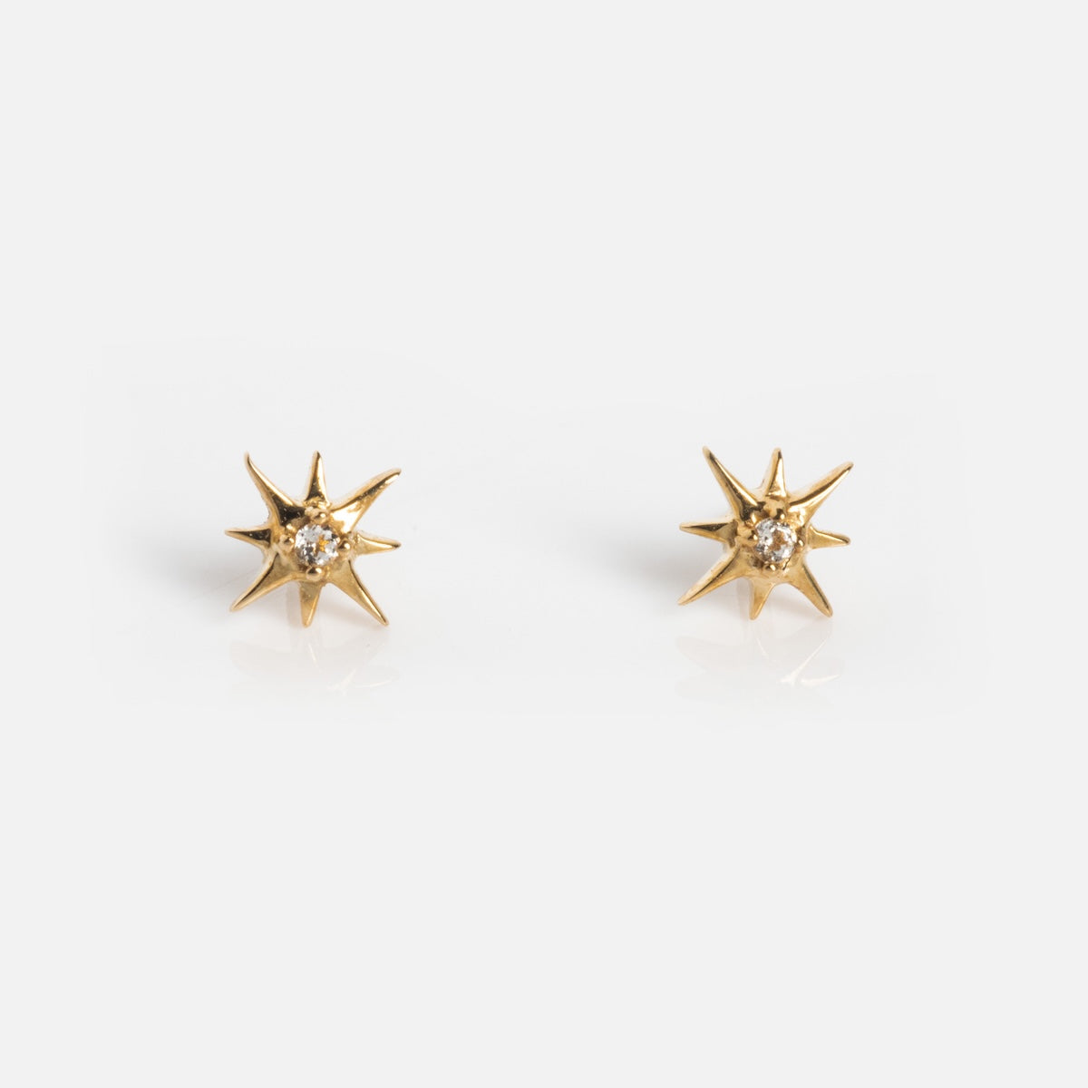 Solid Gold Starburst Flat Back Studs featuring a small clear gemstone at the center, shown on a plain white background.
