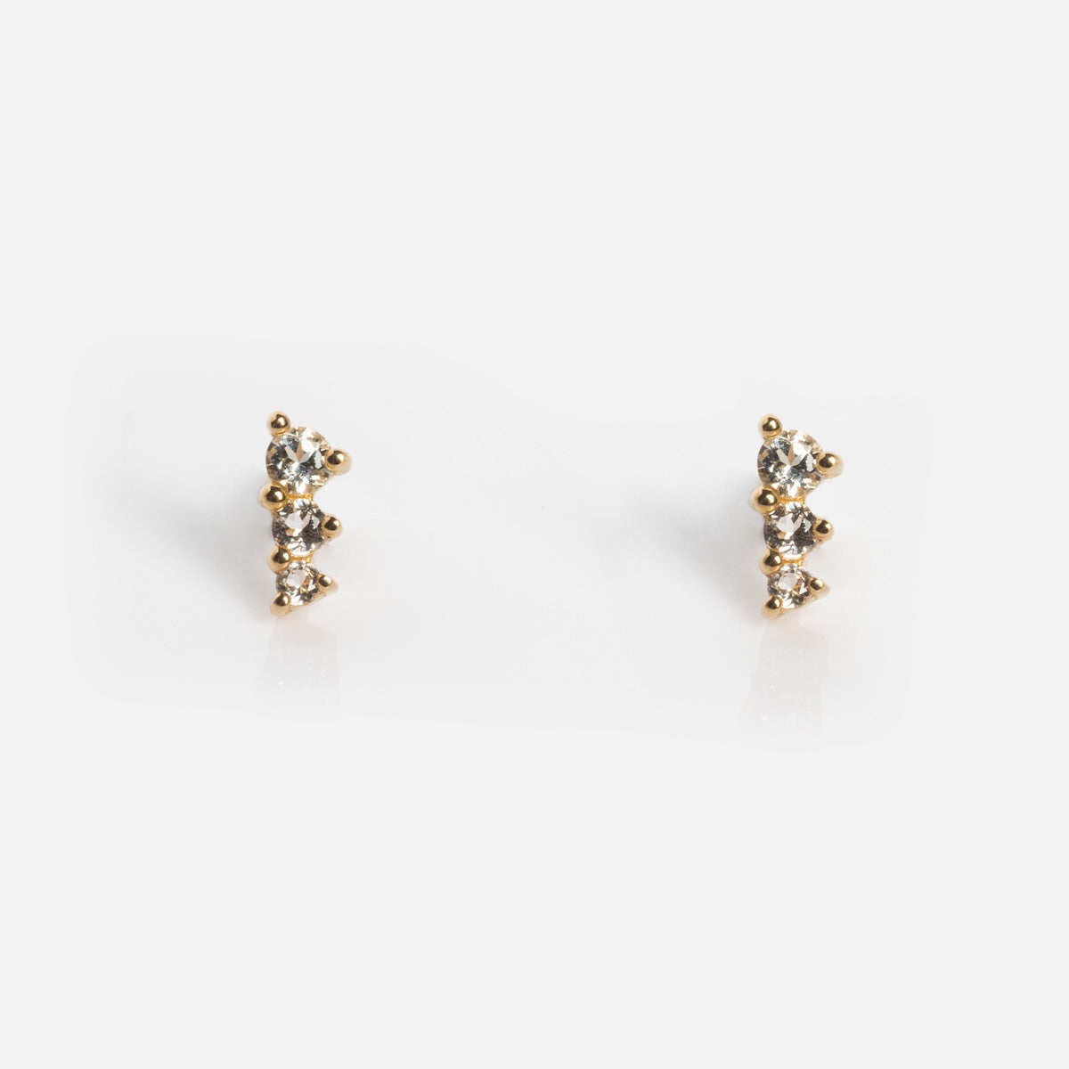 A pair of Solid Gold Tapered Shimmer Flat Back Studs, each with three small round clear gemstones in a vertical line, displayed against a plain white background.