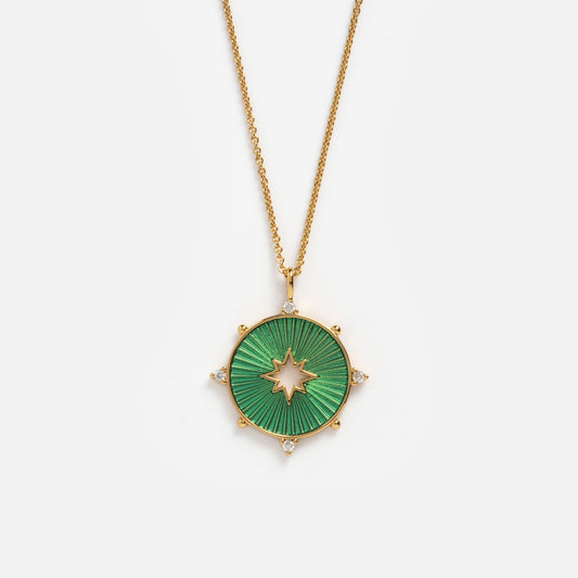 The Starstruck Pendant Necklace features a 14k gold-plated chain with a circular green coin pendant, star-shaped cutout, radiating design, and small clear gemstones along the edge, shown on a plain white background.