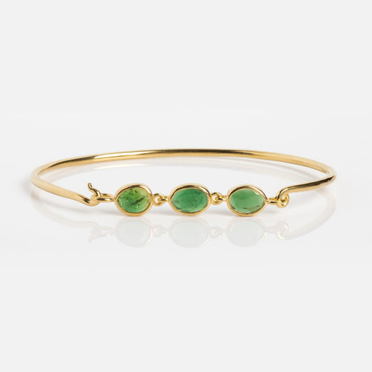 The Jonc Imperial Bracelet by Sophie Deschamps is a gold cuff featuring three oval green stones in a row, displayed on a white background.
