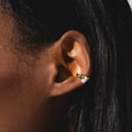 A close-up highlights a gold hoop earring with pearl and gemstone, paired with the delicate Gem Droplet Ear Cuff on smooth, dark skin and straight, dark hair.