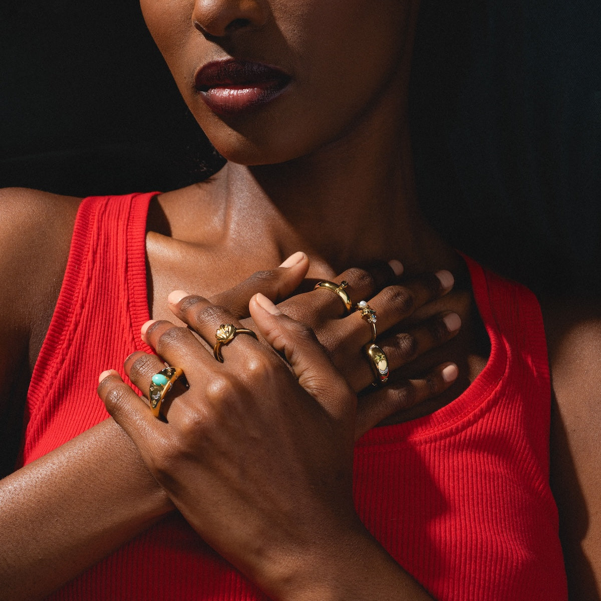 Woman wearing gold rings with a dark background
