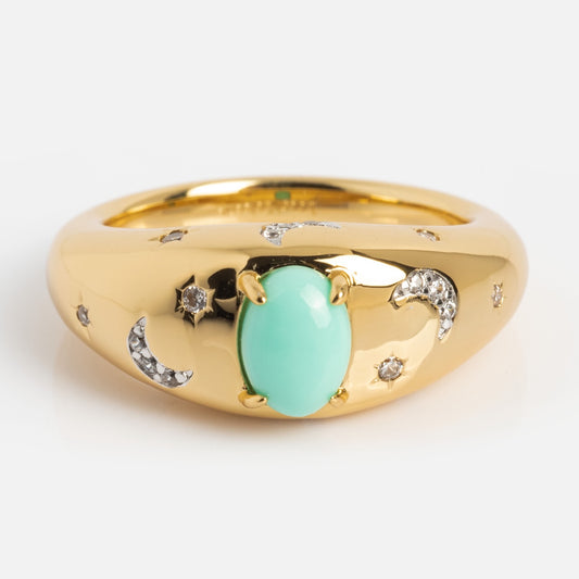 The Turquoise Sky Dome Ring is a gold-plated band with a central oval turquoise stone, engraved crescent moons and stars, and small embedded diamonds along the band for a celestial look.