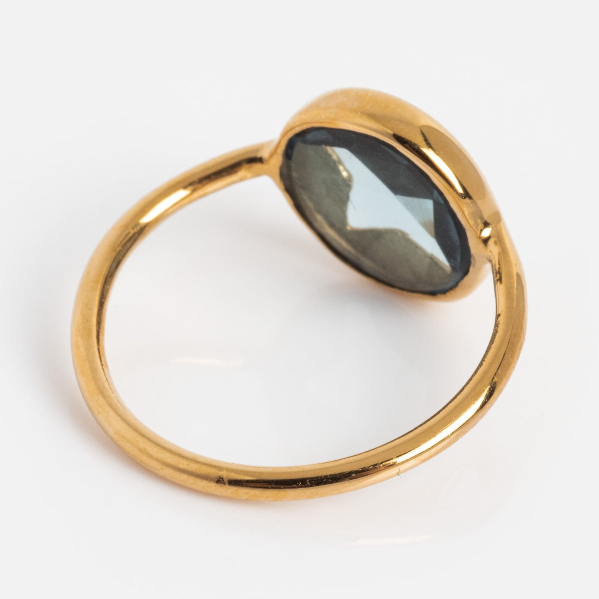 The Maomi Ring features a thin yellow gold plated band and a large oval London blue topaz in a bezel setting, shown against a white background.