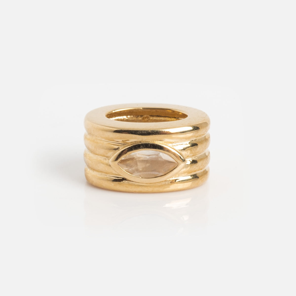 The Solid Gold Bold Birthstone Spacer Charm features a ring shape with three horizontal grooves and a marquise-shaped clear gemstone at the center, shown on a white background.