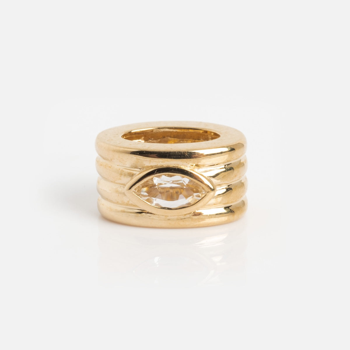 The Solid Gold Bold Birthstone Spacer Charm features a stacked triple-band design with a horizontally set marquise-cut clear gemstone, shown against a plain white background.