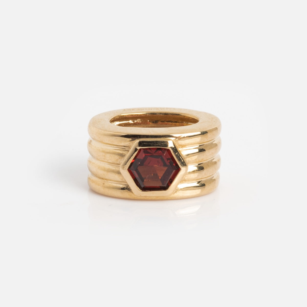 The Solid Gold Bold Birthstone Spacer Charm features four stacked bands and a hexagonal red gemstone at the center, shown against a plain white background.