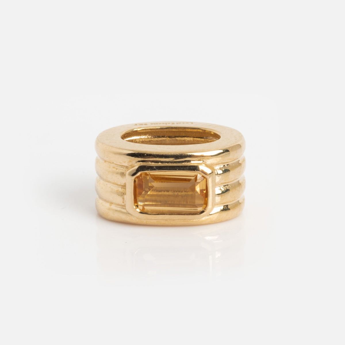 The Solid Gold Bold Birthstone Spacer Charm is a gold ring-shaped bead with horizontal grooves and a rectangular yellow gemstone at its center, shown on a white background.