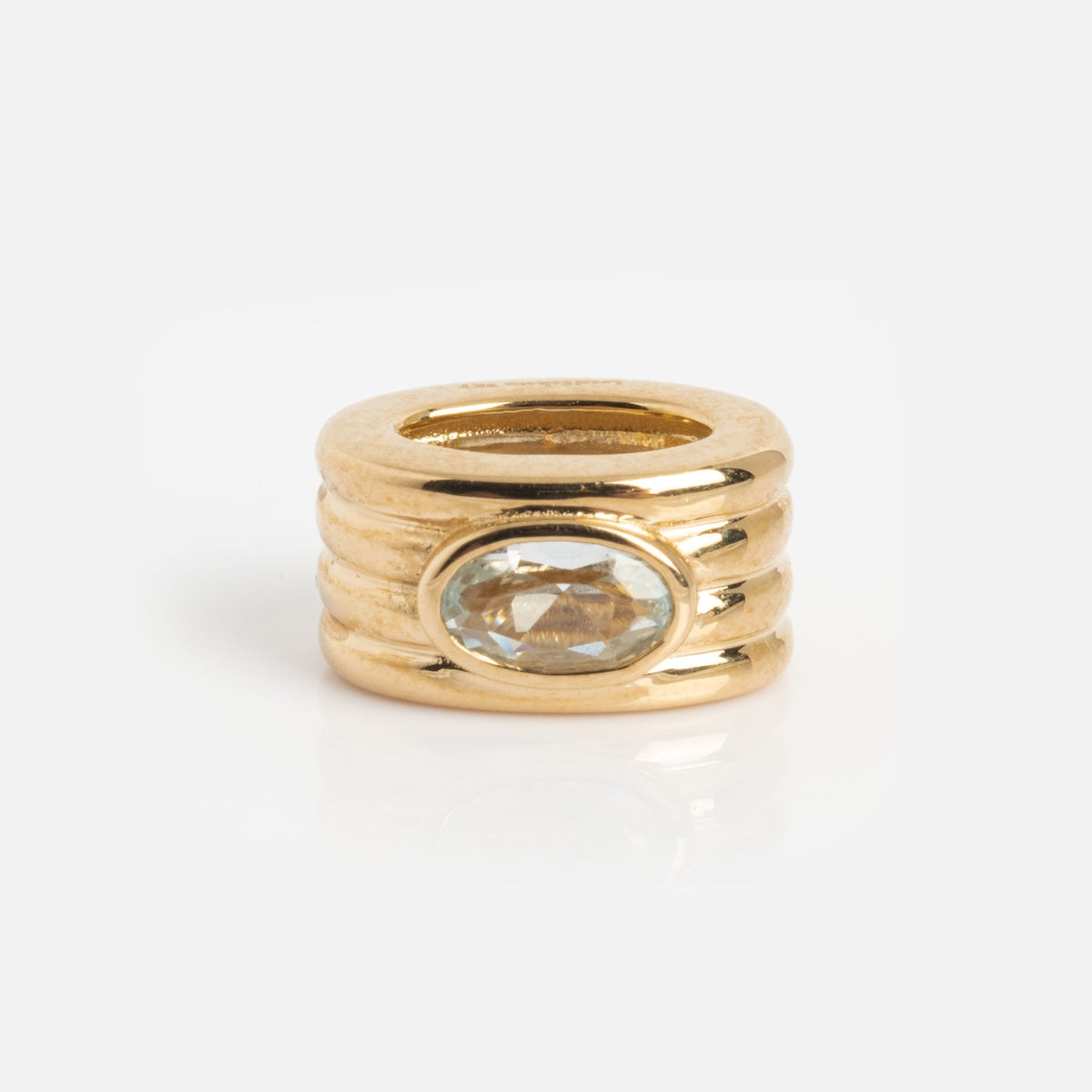 The Solid Gold Bold Birthstone Spacer Charm features a ridged, stacked design with an oval clear gemstone set horizontally at the center, shown on a plain white background.