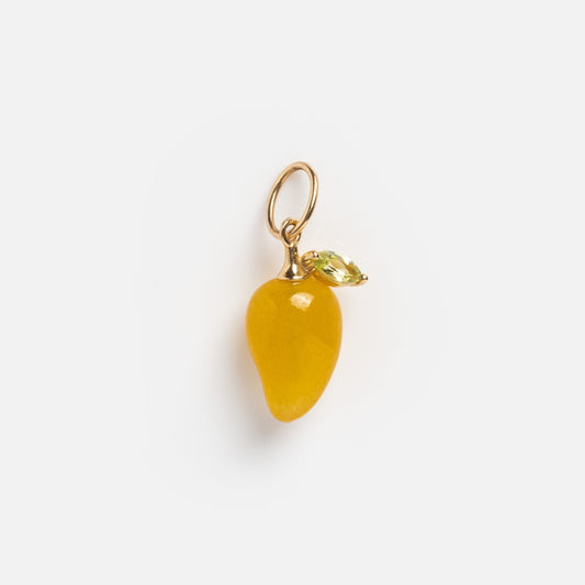 The Solid Gold Foodie Charm is a 9k yellow gold mango-shaped jewelry charm with a small green leaf and a gold loop for attaching to a necklace or bracelet. Perfect for your fruit charm necklace. Shown on a plain white background.