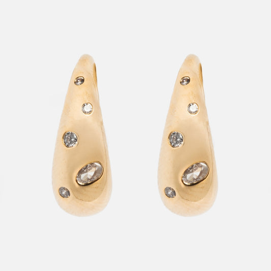 Golden Shimmer Tapered Hoop Earrings by Tai Jewelry, featuring multiple embedded clear gemstones in a teardrop shape, displayed against a plain white background.