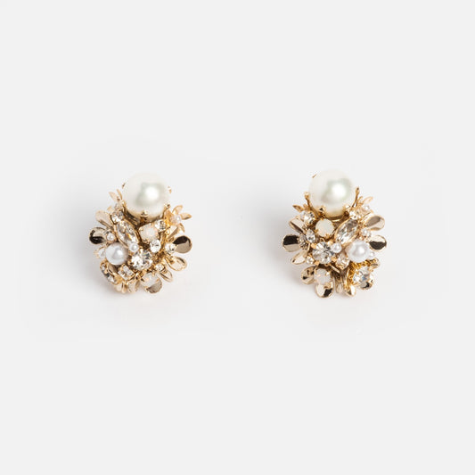 The Luxe Pearl and Crystal Cluster Earrings feature gold plating, clusters of shiny crystals, metallic accents, and a prominent round pearl at the top, all displayed against a plain white background.