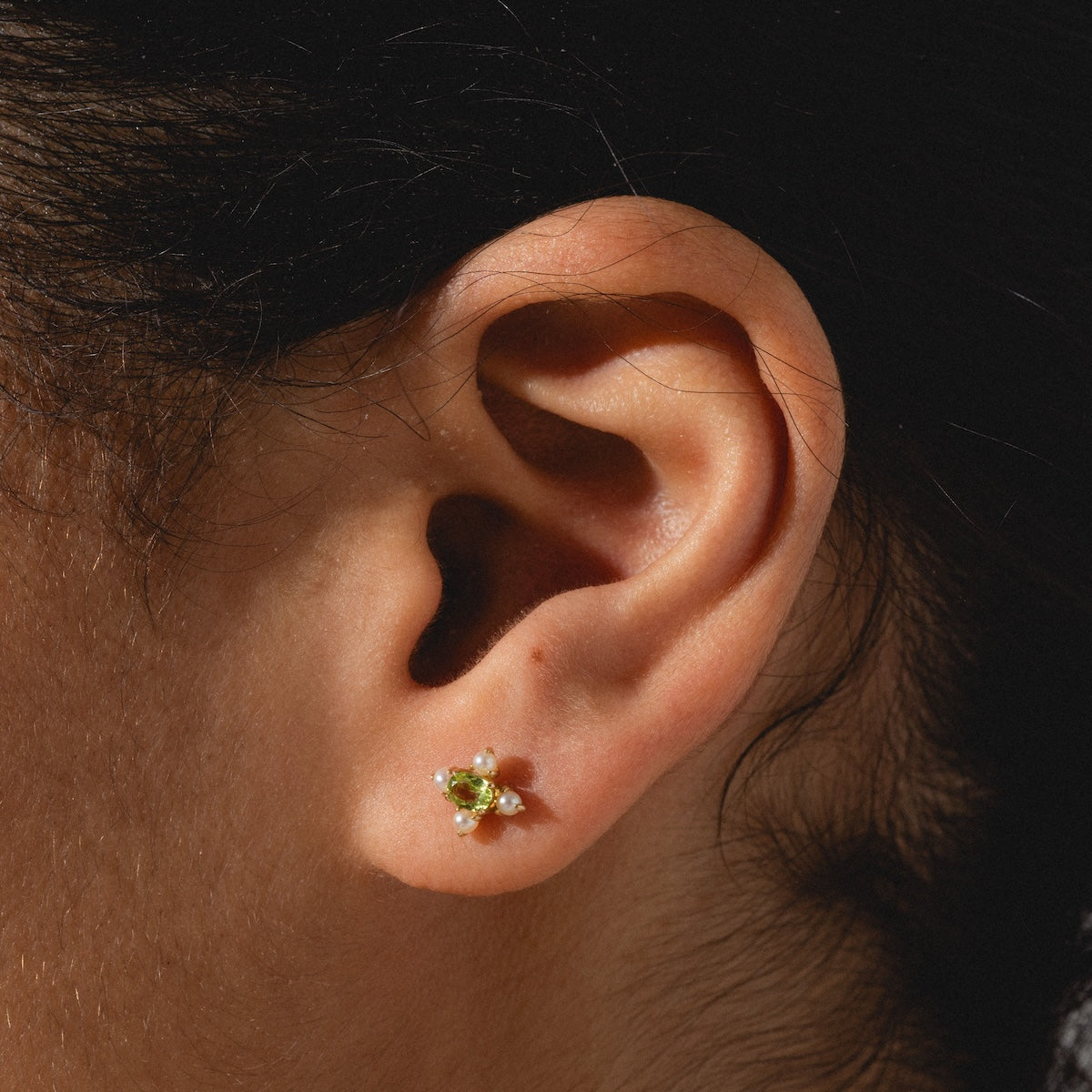 Close up of peridot and pearl earring worn on ear