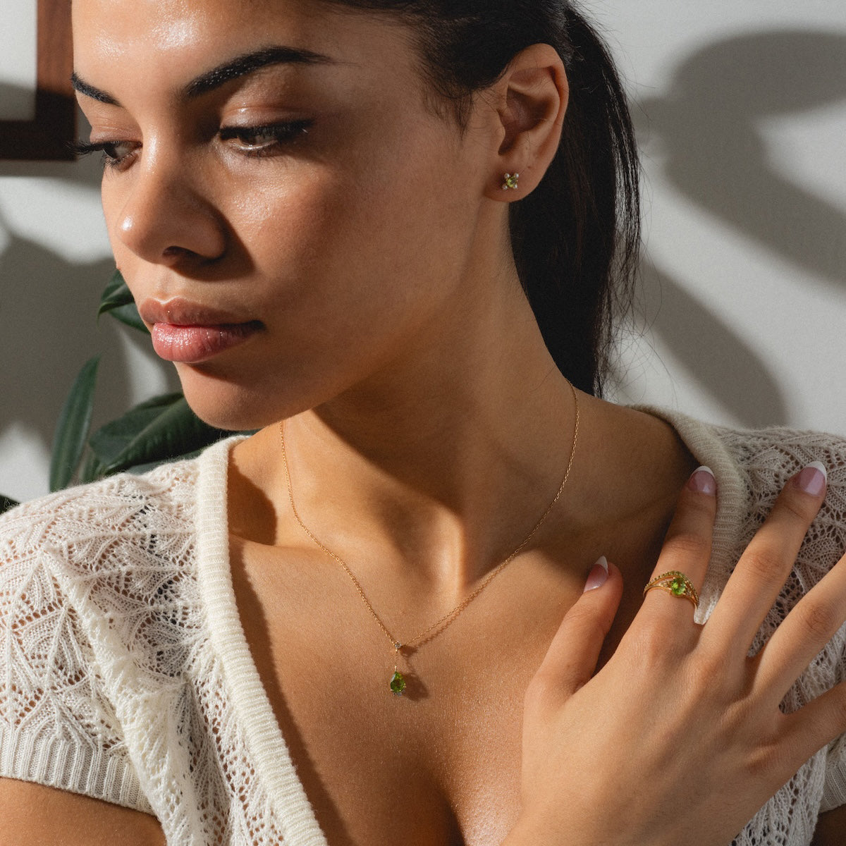 Woman wearing peridot rings, earrings, and necklace