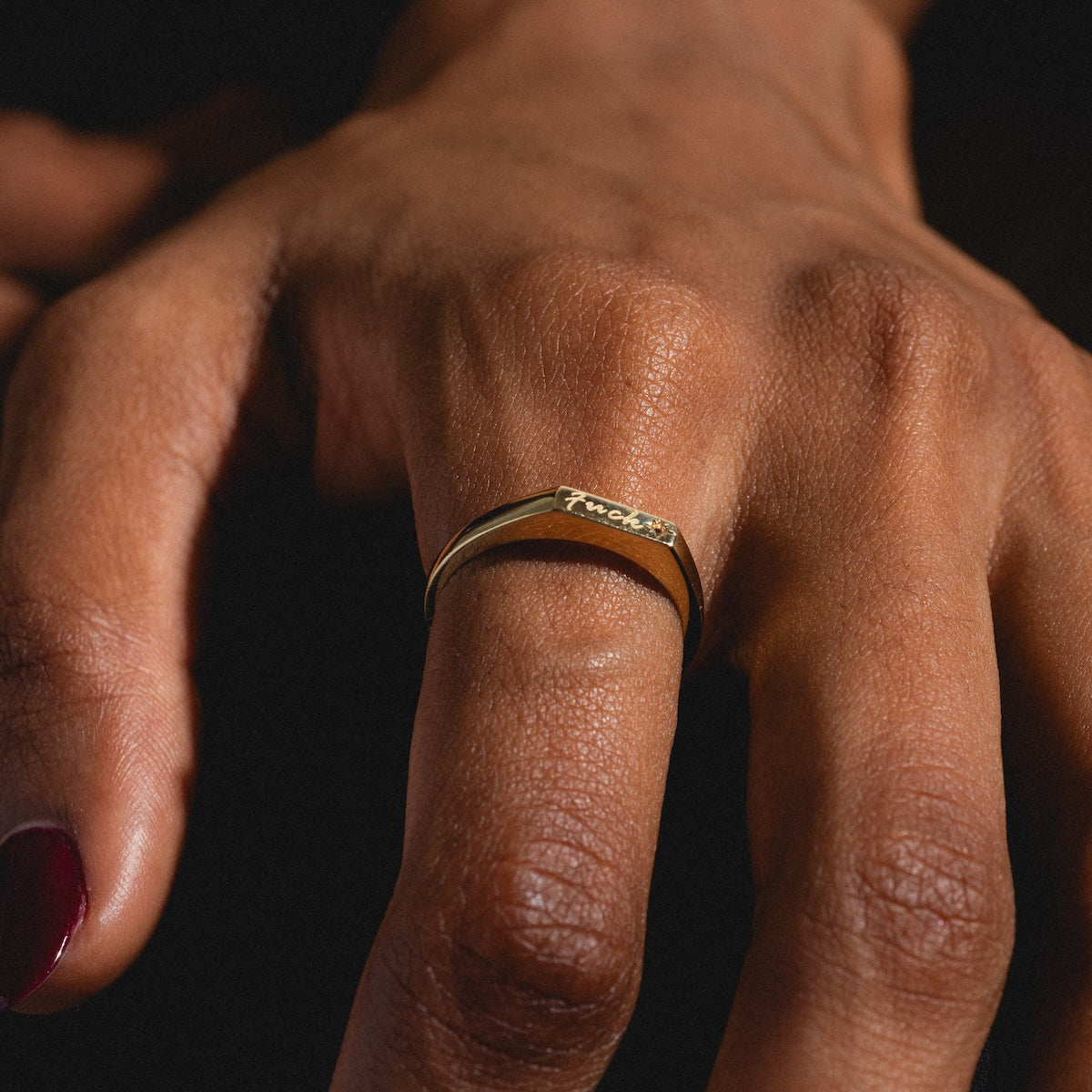 Close up of "fuck" engraved ring on pointer finger