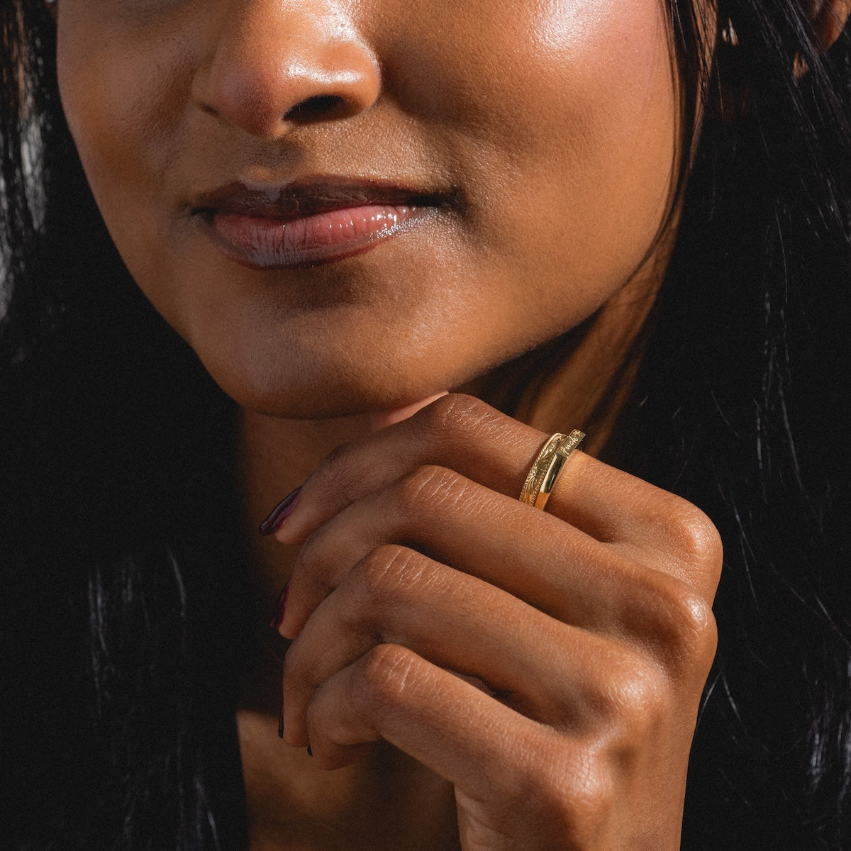 A close-up of a woman’s lower face, her polished nails gently touching her chin as she wears the Solid Gold Tiny Fuck Filigree Stacking Ring Set. Her skin looks smooth and glowing with subtle makeup.