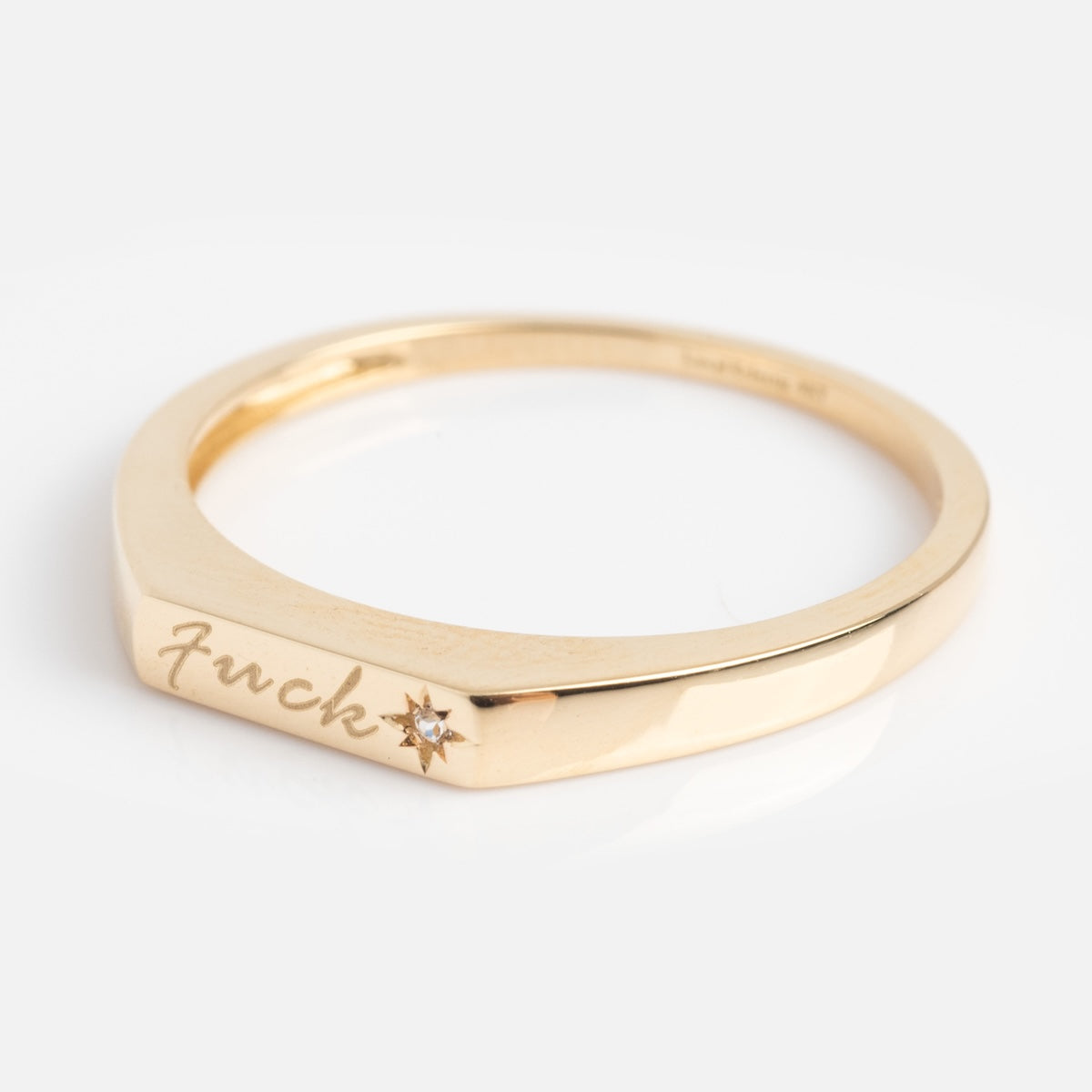 Side view of gold ring with cursive "fuck" engraved