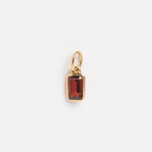 The Solid Gold Birthstone Baguette Charm January Sample is a small gold pendant with a rectangular deep red gemstone in a simple bezel and top loop, shown on a plain white background.