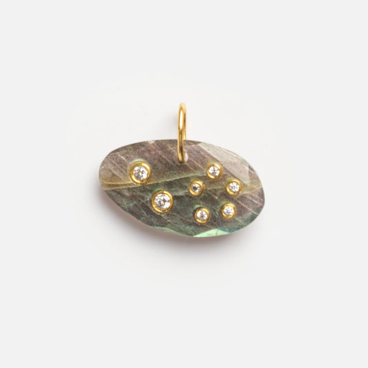 The Labradorite Leo Constellation Charm Sample features an oval iridescent labradorite stone with seven small gemstones in a scattered pattern, set in gold with a top loop for attaching to a chain. Photographed on a plain white background.