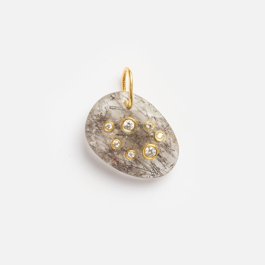 Black Rutile Sagittarius Constellation Charm Sample: Oval-shaped grey stone pendant set in gold, adorned with seven small round clear gemstones and a simple gold loop, shown against a plain white background.