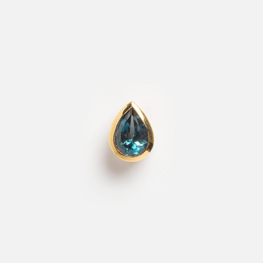 The Solid Gold Pear Gemstone Slider Charm features a lab blue sapphire in a gold bezel setting, teardrop-shaped and shown on a plain white background.