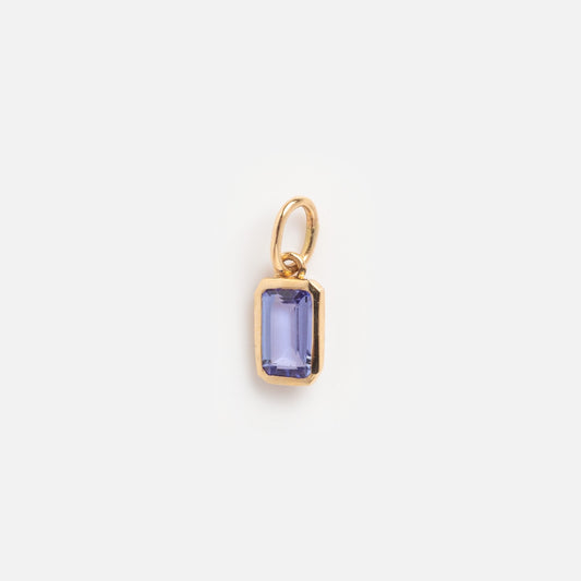 The Solid Gold Birthstone Baguette Charm December Sample is a small gold pendant with a rectangular faceted purple stone and a gold loop, perfect for necklaces or bracelets, shown on a plain white background.