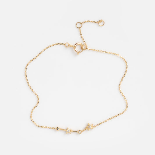 The Solid Gold Zodiac Bracelet Aries Sample features a delicate gold chain with three star-shaped charms, each set with a clear gemstone at the center and finished with an adjustable clasp. Shown on a plain white background.