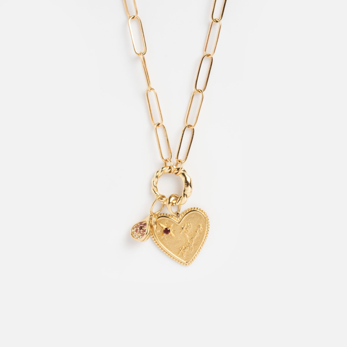 The Solid Gold Perfect Start Charm Holder Necklace features elongated chain links, a heart-shaped pendant engraved with a figure, and a small round charm adorned with pink stones.