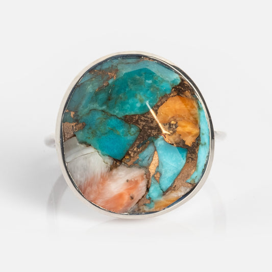 The Statement Oyster Turquoise Ring Sample Silver Size 5 features a 14mm oval oyster turquoise stone with a vivid mosaic of blue, copper brown, orange, and white for a bold, colorful look.