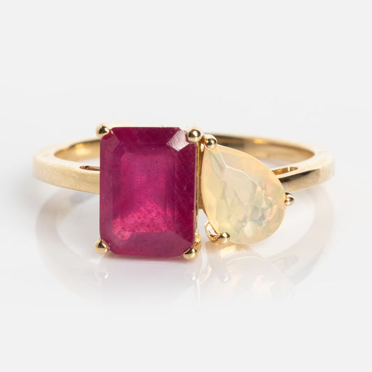 A Customizable Toi et Moi Ring Ruby and Opal Sample Size 7 features a gold band with a rectangular red gemstone and a pear-shaped pale yellow gemstone set side by side against a white background.