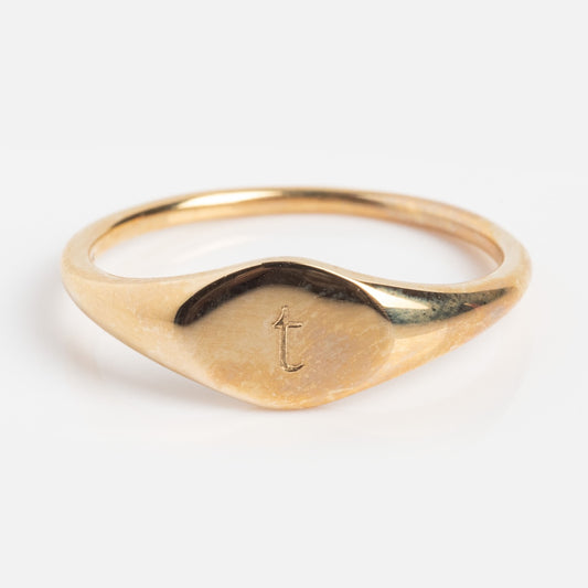 The Solid Gold Engravable Simple Signet Ring Sample t Size 5 features a minimalist gold band with a small lowercase t engraved on its flat top, showcased against a plain white background.