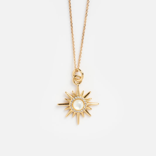 The Starburst Necklace Sample features a gold sunburst pendant with a central mother of pearl and cubic zirconia accents, hanging from a delicate chain, displayed on a plain white background.