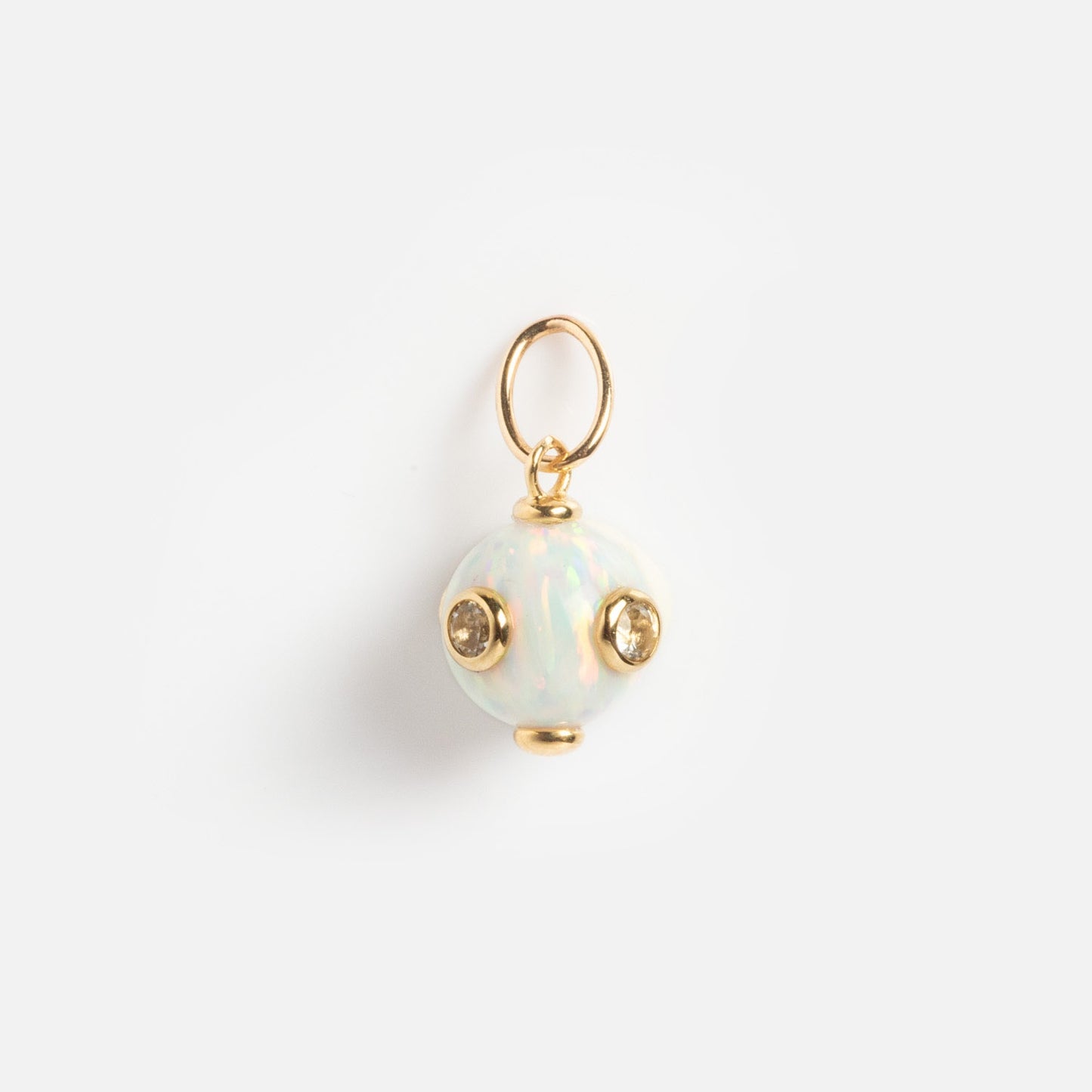 The Solid Gold Statement Charm is a small, round opal charm featuring three gold-set gemstones and a gold loop on top, perfect for unique jewelry lovers. Shown against a plain white background.