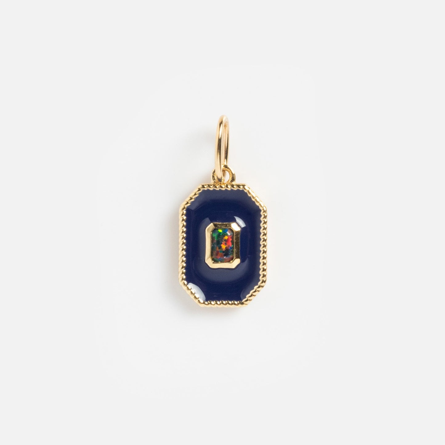 The Solid Gold Statement Charm features a gold pendant with a dark blue octagonal border and a multicolored gemstone center, creating a stunning necklace that stands out beautifully against a plain white background.