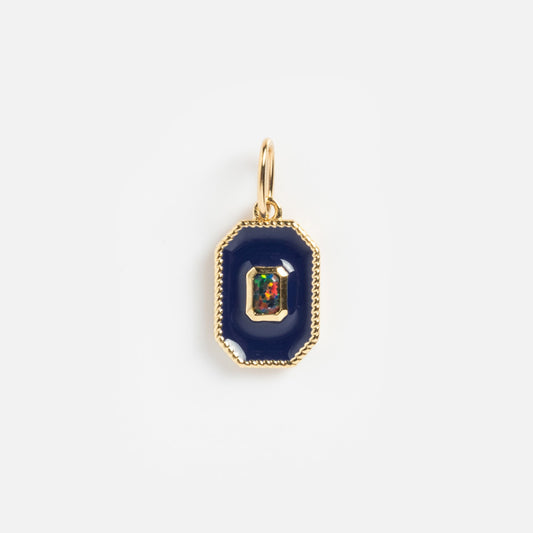 The Solid Gold Statement Charm features a gold pendant with a dark blue octagonal border and a multicolored gemstone center, creating a stunning necklace that stands out beautifully against a plain white background.