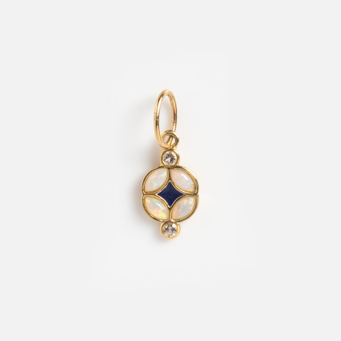 The Solid Gold Statement Charm is a round pendant with four iridescent opal-like stones circling a dark blue center, plus two small clear gems above and below—perfect for those who love unique, eye-catching jewelry.
