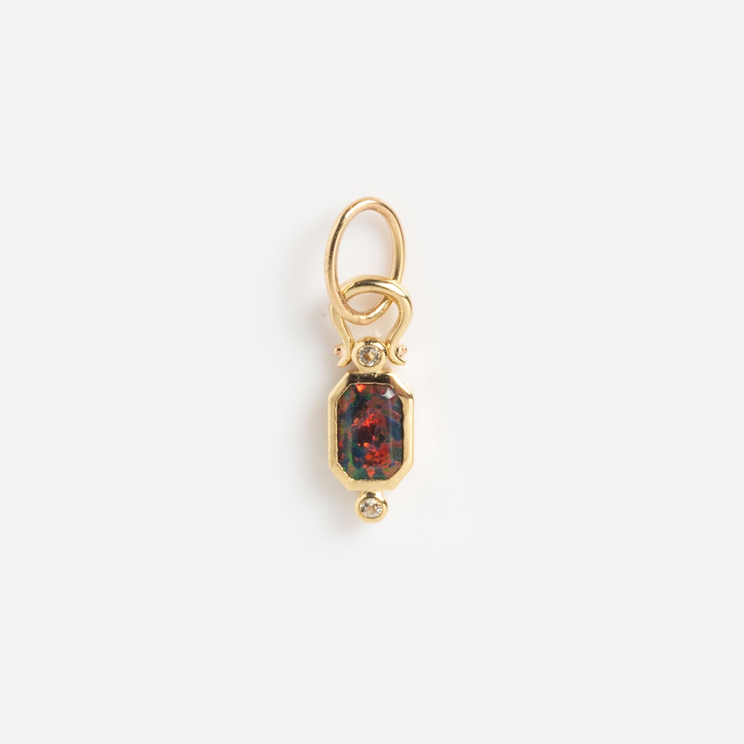 The Solid Gold Statement Charm is a necklace with a gold pendant, an octagonal multicolored gemstone at the center, clear stones above and below, and two interlocking gold loops for a truly unique jewelry piece.